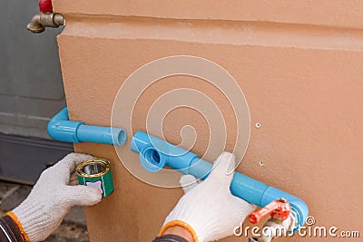 Plumber hand weld blue plastic water pipe by using glue sealant Stock Photo