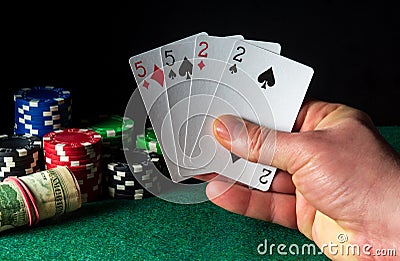 Poker cards with two pairs combination. Close-up of a gambler hand is holding playing cards in casino. Chips on the green table Stock Photo