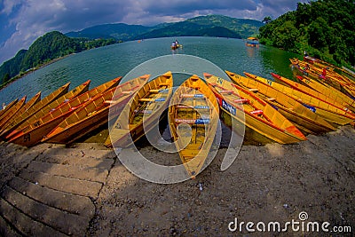 POKHARA, NEPAL - NOVEMBER 04, 2017: Close up of wooden yellow boats in a row at Begnas lake in Pokhara, Nepal, fish eye Editorial Stock Photo