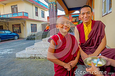 POKHARA, NEPAL - OCTOBER 06 2017: Unidentified Buddhist monk teenager holding in his hand a metallic bowl with soup and Editorial Stock Photo