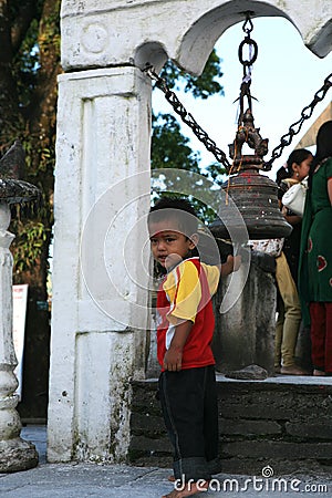 POKHARA, NEPAL. 25 September 2008: Little boy-Hindu pilgrim at a sacred bell at the temple of goddess Durga. Editorial Stock Photo