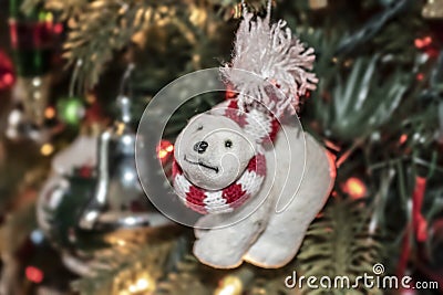 Polar bear Christmas ornament with red & white scarf and crooked nose and funny expression against bokeh decorated tree withh ligh Stock Photo