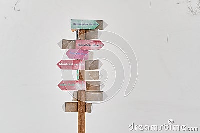 Pole with arrows pointing to various world cities, in Les Sybelles ski domain, during heavy snowfall Stock Photo