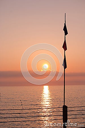 A pole silhouetted against sunset over sea Stock Photo