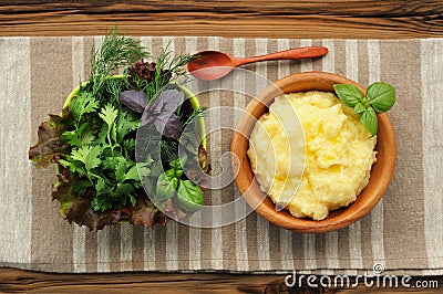 Polenta with basil shoot in wooden bowl with green salad and woo Stock Photo