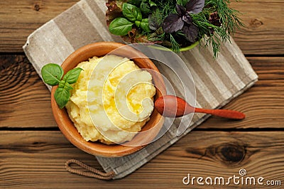 Polenta with basil shoot in wooden bowl with green salad and woo Stock Photo