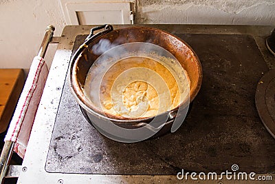 Polenta cooked in a copper cauldron on a wood stove Stock Photo