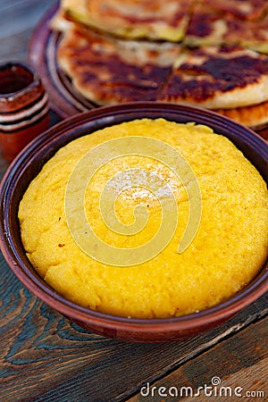 Polenta is a dish made from corn flour, served with a book and cheese. Stock Photo