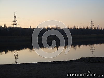 Poles with wires that transmit high-voltage current. Background of the evening sky with the sun Stock Photo