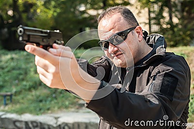 Police agent bodyguard gun pointing pistol to attacker. Front view Stock Photo
