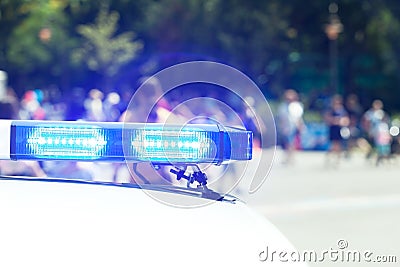 Police car flashing lights in focus, blurred people in the background. Law enforcement concept. Stock Photo