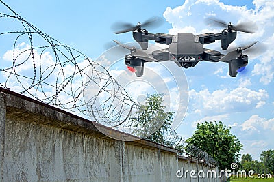 Police drone patrols the area across the sky. Guarding the wall with barbed wire drone with blue and red beacon Stock Photo
