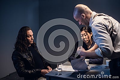 A police investigator with a gun in a holster meets with a man suspected of theft in the presence of a lawyer at the Stock Photo