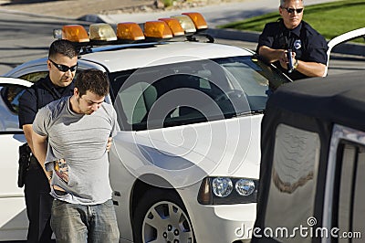 Police Officer Arresting Young Man Stock Photo