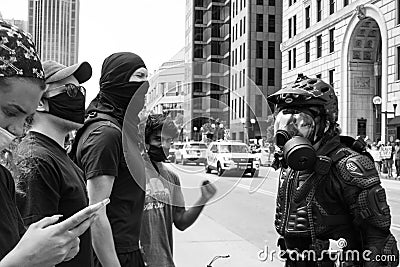 Police officer in body armor faces off with a crowd of protestors Editorial Stock Photo