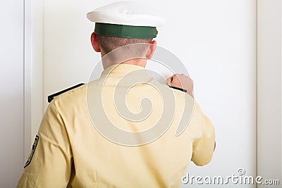 Police officer knocking on front door of home Stock Photo