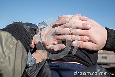 A police officer puts handcuffs on the hands of a bandit Stock Photo