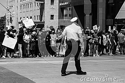 A police officer stands in front of a line of protestors who have linked arms in downtown Columbus Ohio Editorial Stock Photo