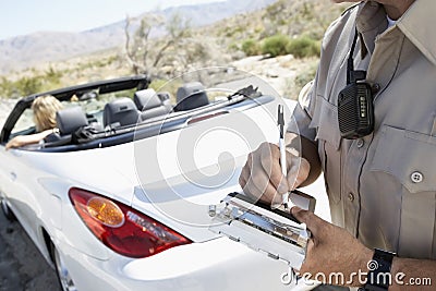 Police Officer Writing Traffic Ticket To Woman Sitting In Car Stock Photo
