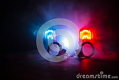 Police raid at night and you are under arrest concept. Silhouette of handcuffs with police car on backside. Image with the Stock Photo