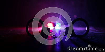 Police raid at night and you are under arrest concept. Silhouette of handcuffs with police car on backside. Image with the Stock Photo