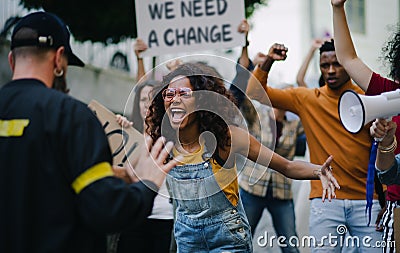 Police stopping group of people activists with raised fists protesting on streets, BLM demonstration concept. Stock Photo