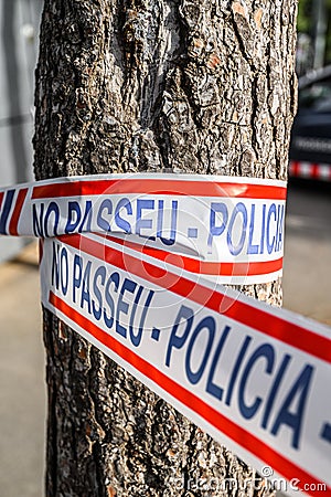 Police tape wrapped around a tree to limit the perimeter of a crime scene or a suspected bomb site. 03.01.2020 Barcelona, Spain Editorial Stock Photo