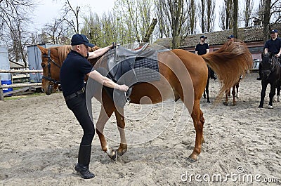 Police trainer leading horse with a horseman in a circle of a manege Editorial Stock Photo