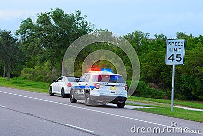 Police truck vehicle pulling over a sports car by speed limit sign Editorial Stock Photo