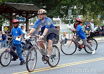 Policeman on bike patrol is joined in patroling by kids on bikes Editorial Stock Photo