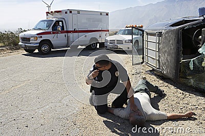 Policeman Checking Pulse Of Car Crash Victim Stock Photo