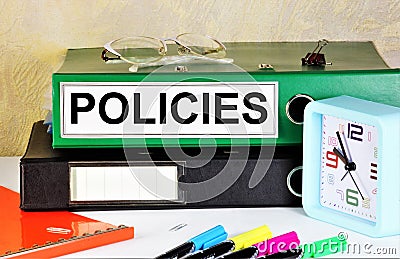 Policies. An inscription with a folder on the background of the planning clock. Stock Photo