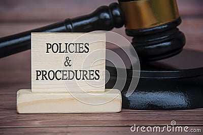 Policies and procedures text engraved on wooden block with gavel background. Policy and procedure concept Stock Photo