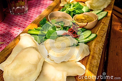 Polish pierogi on wooden board with green salad Stock Photo