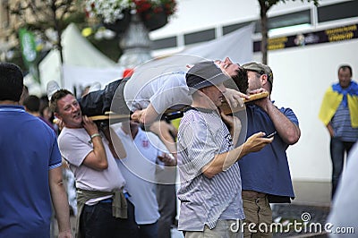 Polish soccer male fans carrying their drunk fellow on the stretcher on the street Editorial Stock Photo