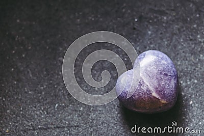 Polished lepidolite lilac stone in the shape of a heart on a black background Stock Photo
