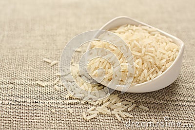 Polished long rice grains in white ceramic bowl Stock Photo