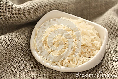 Polished long rice grains in white ceramic bowl Stock Photo