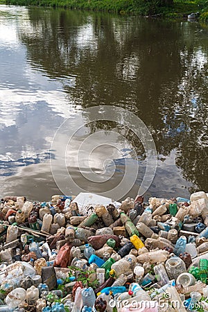 Pollution of the lake, fresh water. Plastic trash, dirty waste on the beach on a summer day. beautiful nature and peoplelessness. Stock Photo