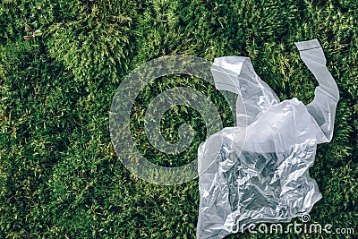 Pollution problem concept. Disposable plastic bag on green moss, grass background. Top view. Copy space. Environmental Stock Photo