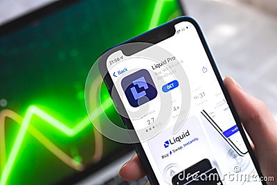 Liquid Pro crypto currency wallet app. Hand with smartphone, logo on the screen. Stock chart background photo Editorial Stock Photo