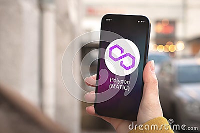Polygon MATIC cryptocurrency symbol, logo. Business and financial concept. Hand with smartphone, screen with crypto icon Editorial Stock Photo