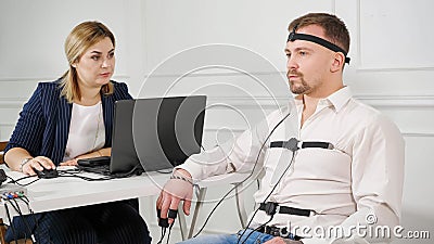 Polygraph technician reads questions from a laptop. man connected to the lie detector circuit Stock Photo