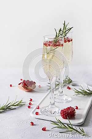 Pomegranate Christmas cocktail with rosemary, sparkling wine on white table. Xmas Holiday drink Stock Photo