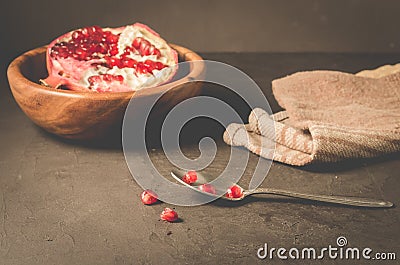 pomegranate fruit in a wooden bowl/pomegranate fruit in a wooden bowl and seeds on the table and in a spoon, selective focus Stock Photo