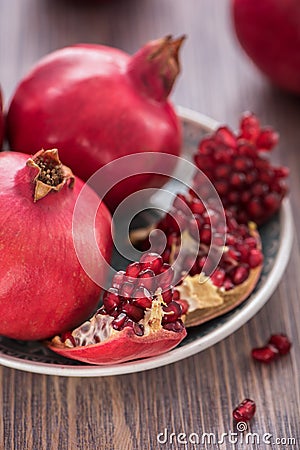 Pomegranate juice in a glass with fresh pomegranates around with scattered seeds on wooden background Stock Photo