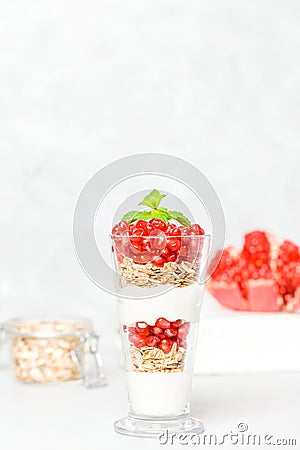 Pomegranate parfait - sweet organic layered dessert with granola flakes, yogurt and ripe fruit seeds. Stock Photo