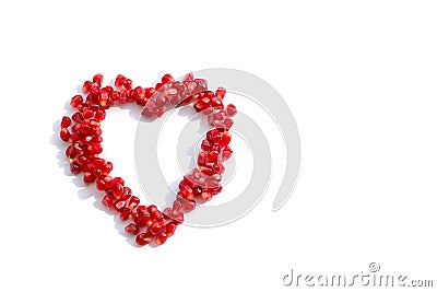 Pomegranate seeds scattered in the shape of a heart on white background. love concept Stock Photo