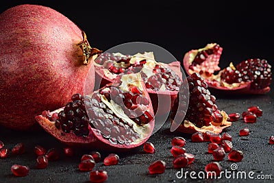 Pomegranate split open to reveal clusters of seeds on black background Stock Photo