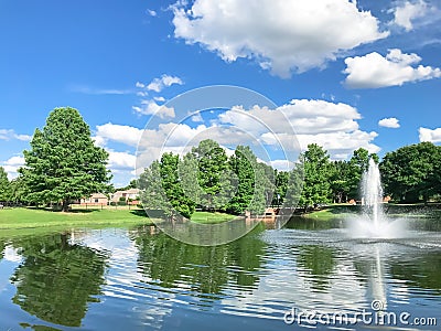 Pond with cloud reflection and water fountain in small American neighborhood Stock Photo